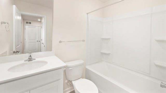 Primary bathroom with double sinks, white cabinets and counters