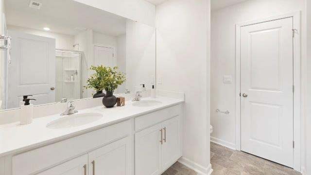 Primary bathroom with double sinks, white cabinets and counters