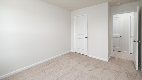 Carpeted bedroom with view of entryway and closet doors