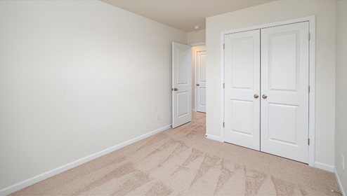 Carpeted bedroom with view of entryway and closet doors