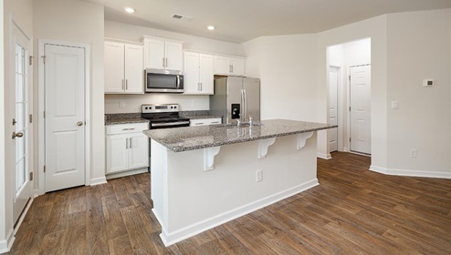 Kitchen and island with white cabinets, subway tile backsplash, and stainless steel appliances