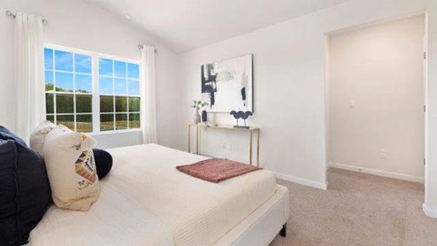 Fergus Crossing Townhomes Model Carpeted bedroom with large window, view of walk in closet