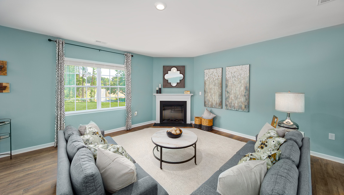 Open family room with fireplace, windows, and view of dining and kitchen