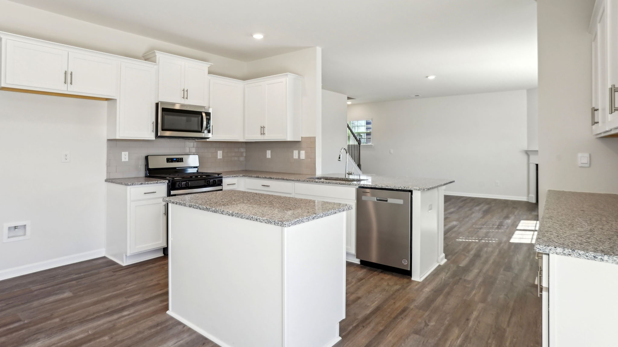 Kitchen and island with white counters, subway tile backsplash and stainless steel appliances