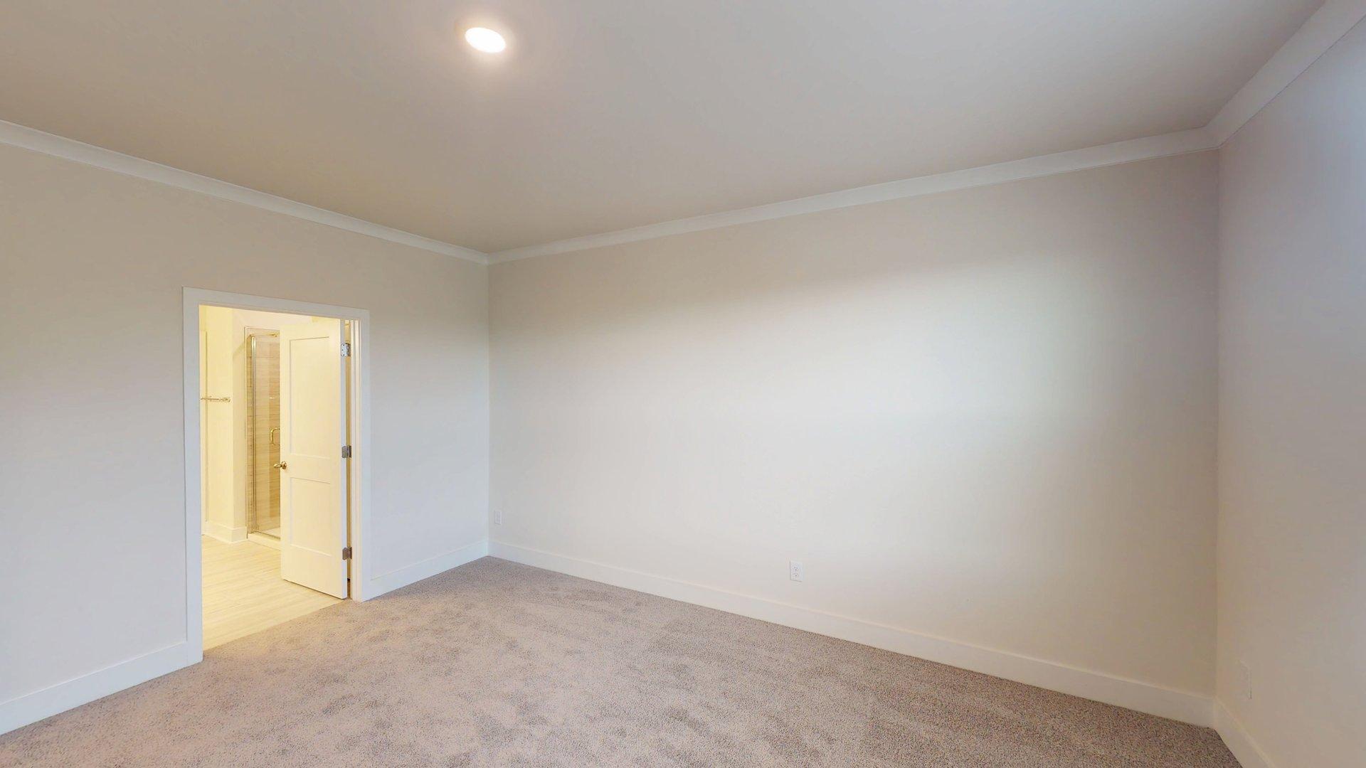 Primary bedroom with beige carpet, and large window. New Homes in Charlotte, North Carolina
