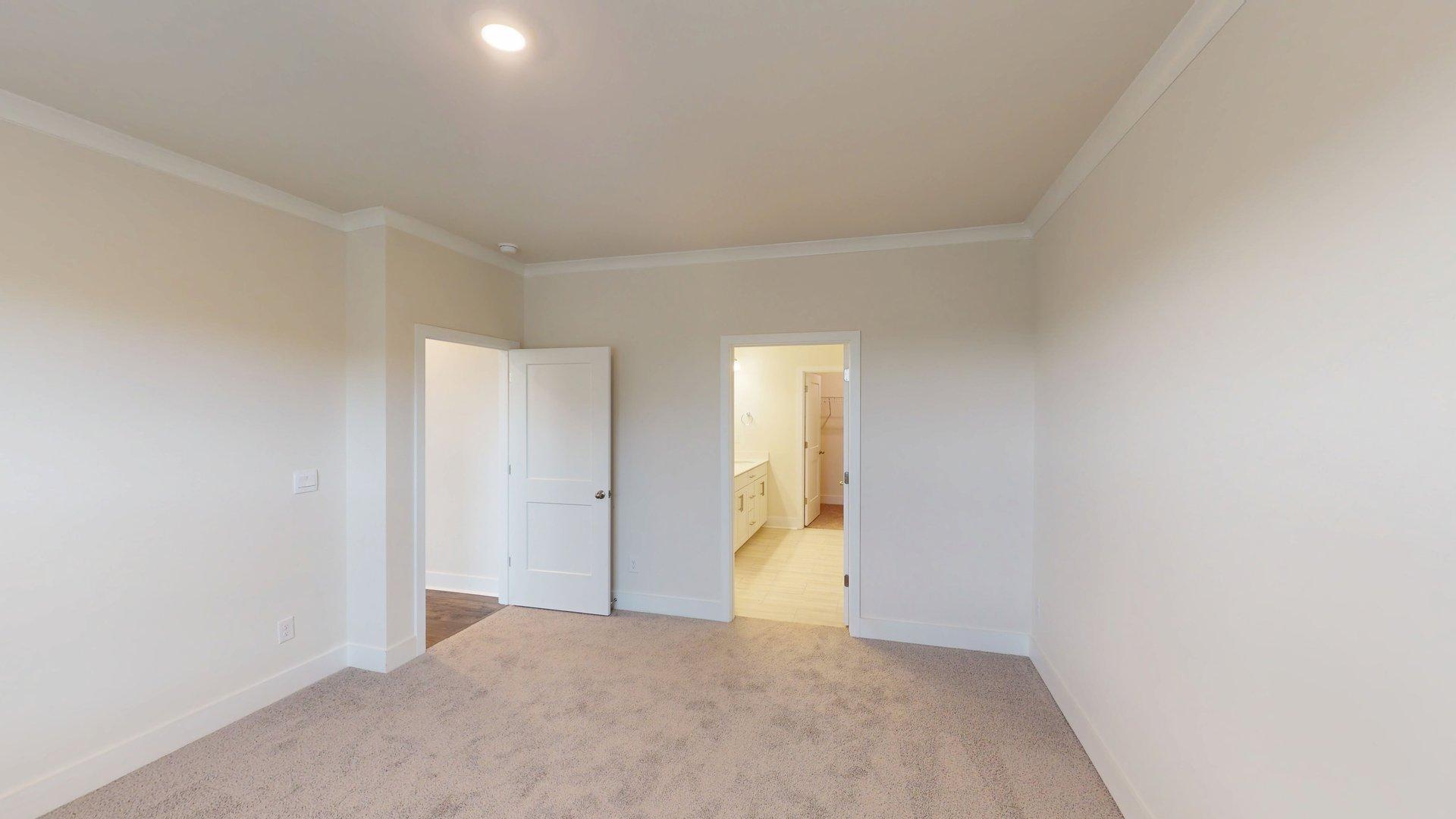 Primary bedroom with beige carpet, and large window. New Homes in Charlotte, North Carolina
