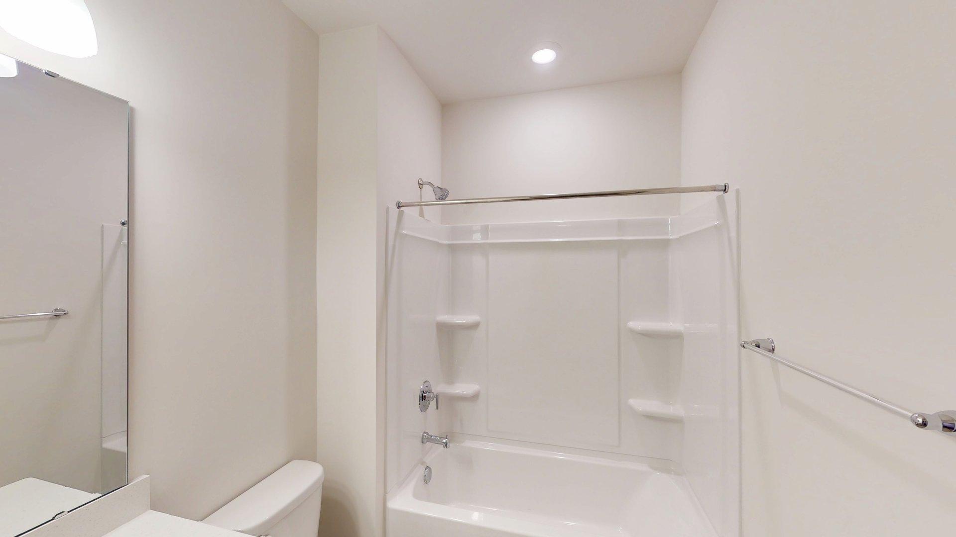 Bathroom with grey cabinets, and bathtub shower combination. Primary bathroom with grey cabinets, white countertop, double sink vanity and glass door shower. New Homes in Charlotte, North Carolina