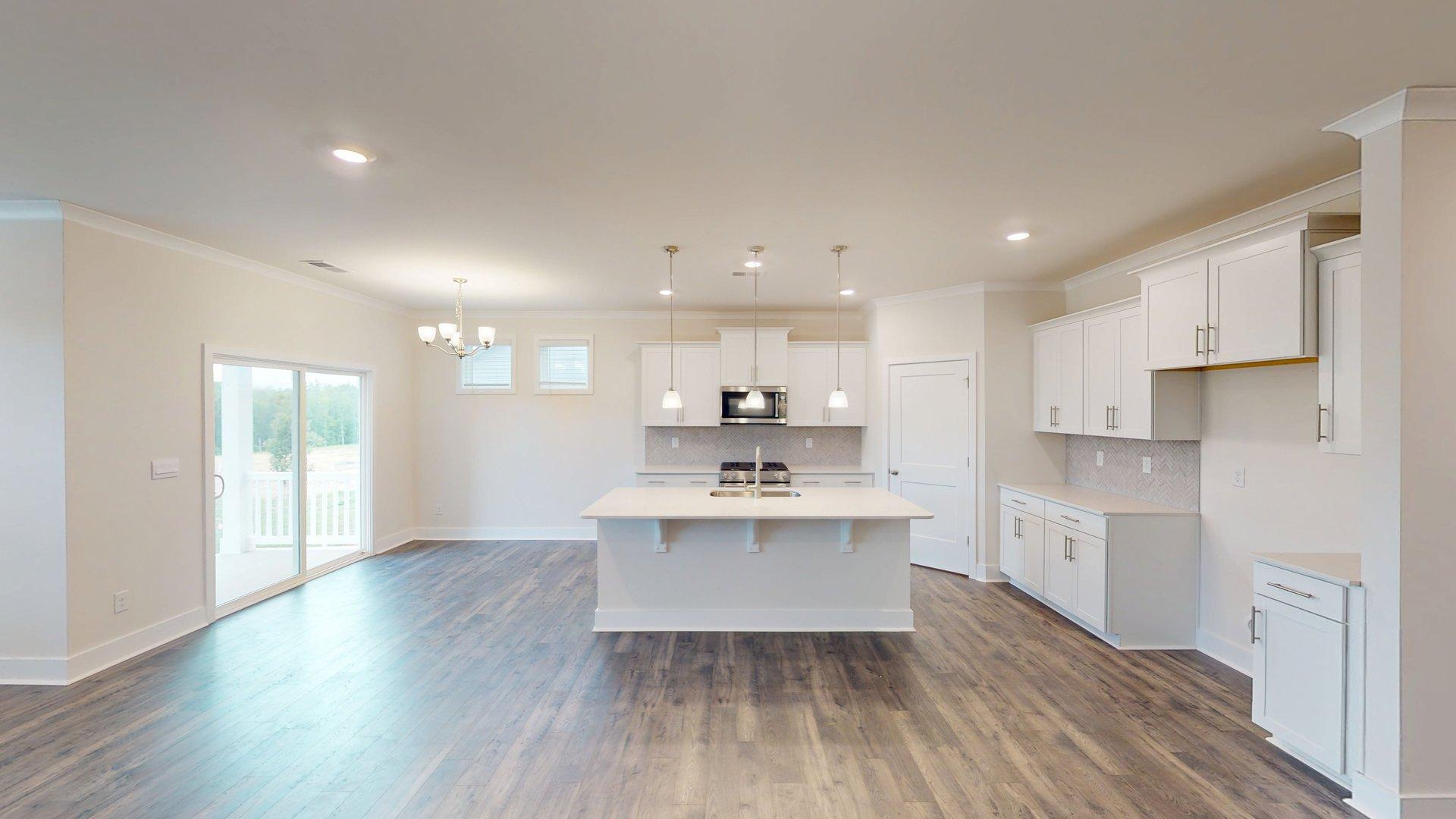Kitchen and island with grey cabinets, white countertops, and stainless steel appliances. New Homes in Charlotte, North Carolina