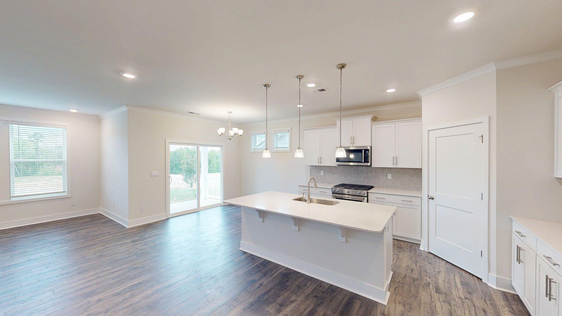 Kitchen and island with grey cabinets, white countertops, and stainless steel appliances. New Homes in Charlotte, North Carolina
