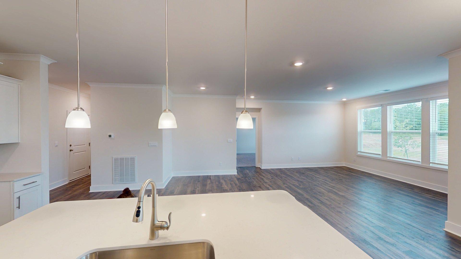 Kitchen and island with grey cabinets, white countertops, and stainless steel appliances. New Homes in Charlotte, North Carolina