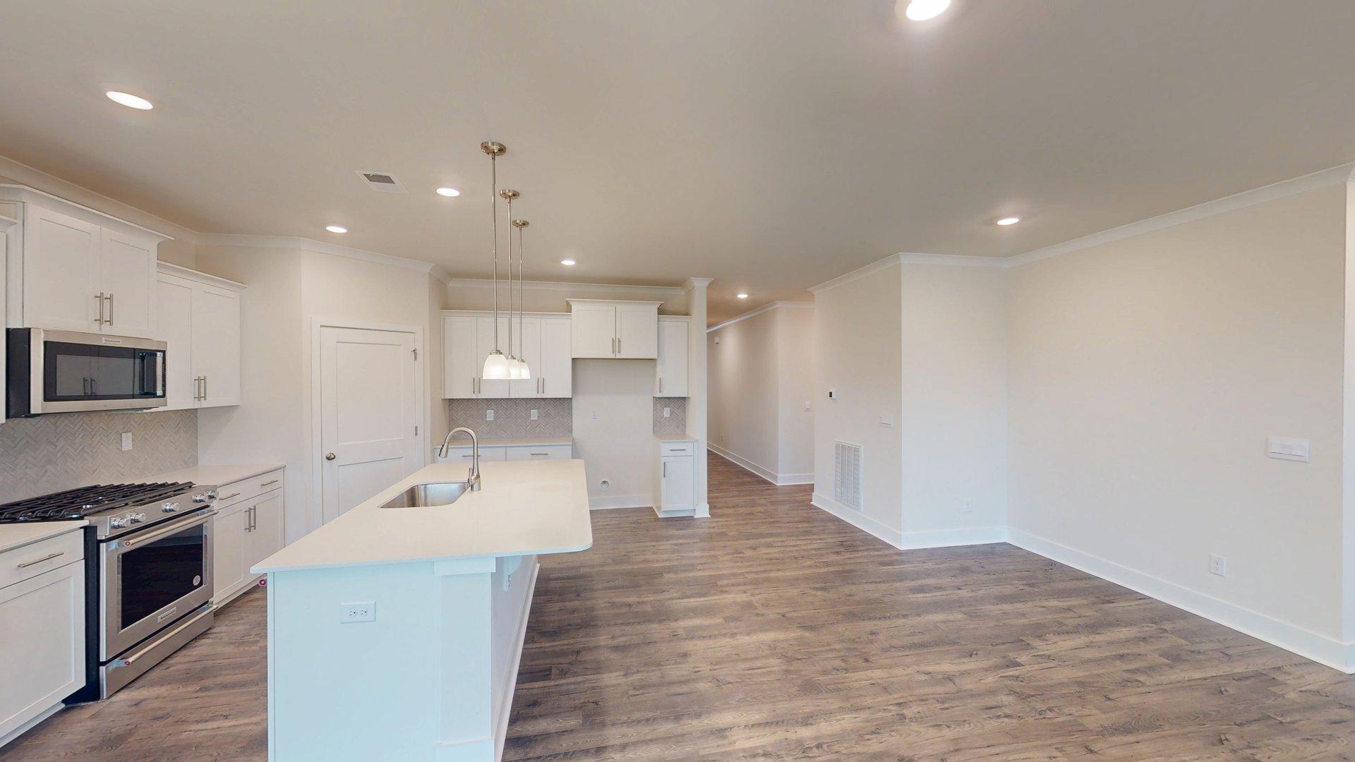Kitchen and island with grey cabinets, white countertops, and stainless steel appliances. New Homes in Charlotte, North Carolina