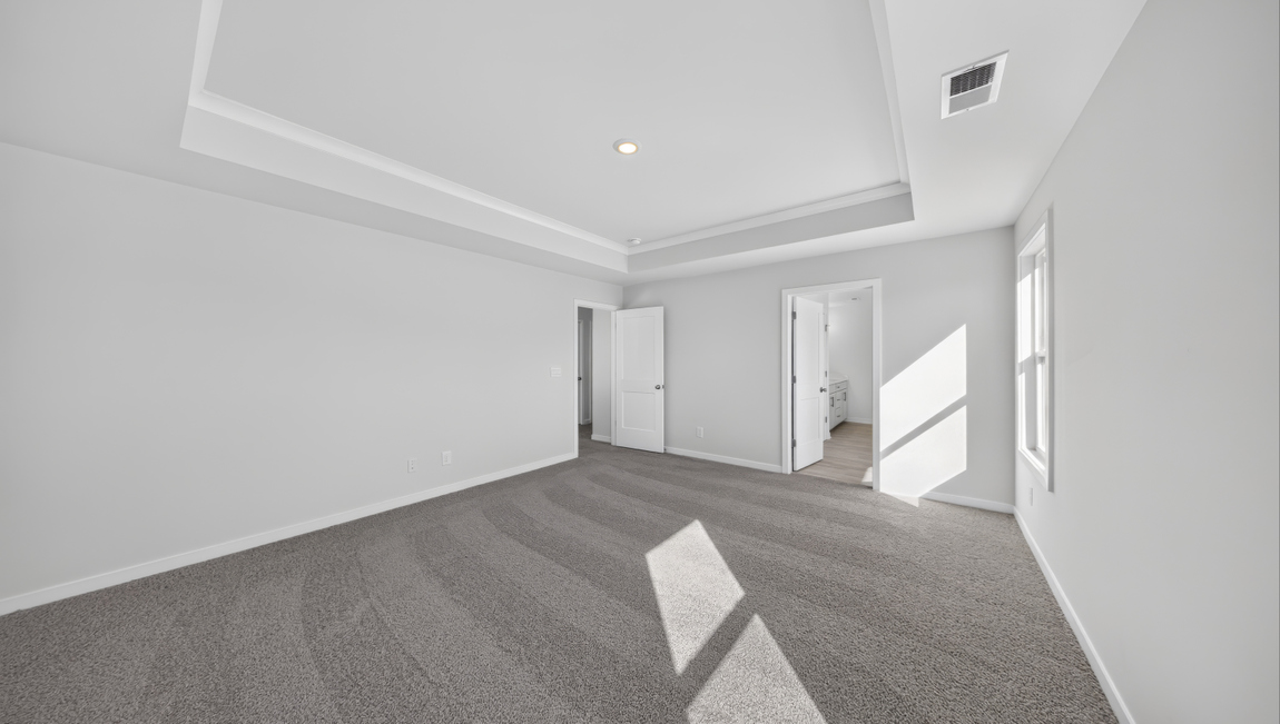 Primary carpeted bedroom with windows