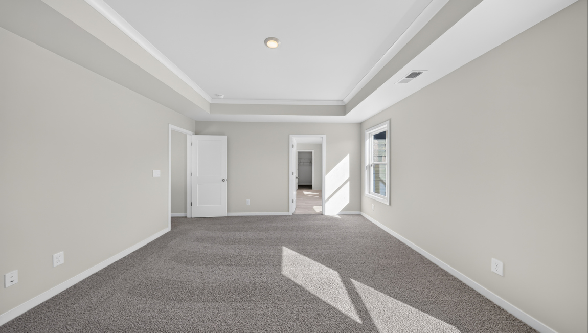 Primary carpeted bedroom with windows