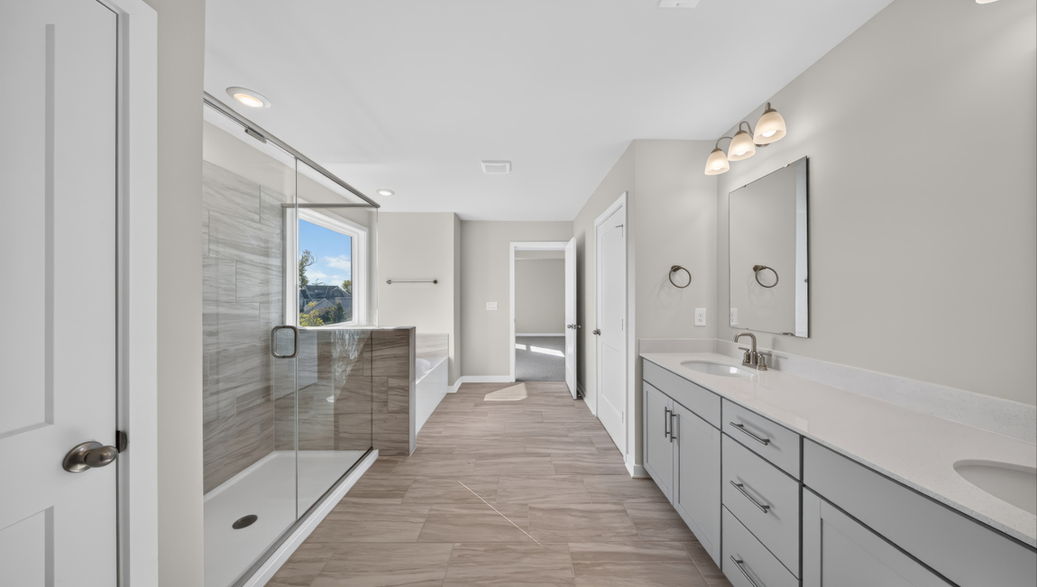Primary bathroom with standing glass shower and double sinks