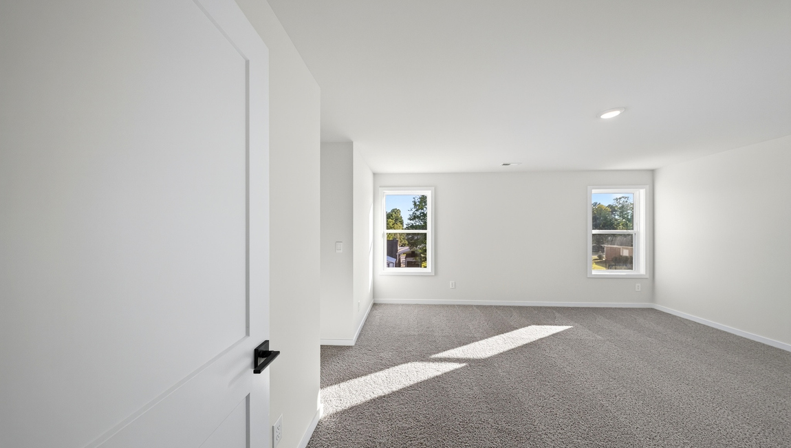Primary carpeted bedroom with windows