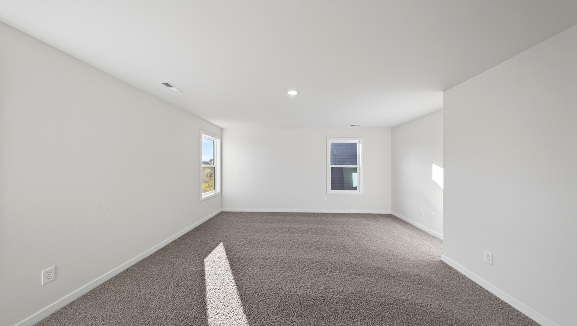 Primary carpeted bedroom with windows