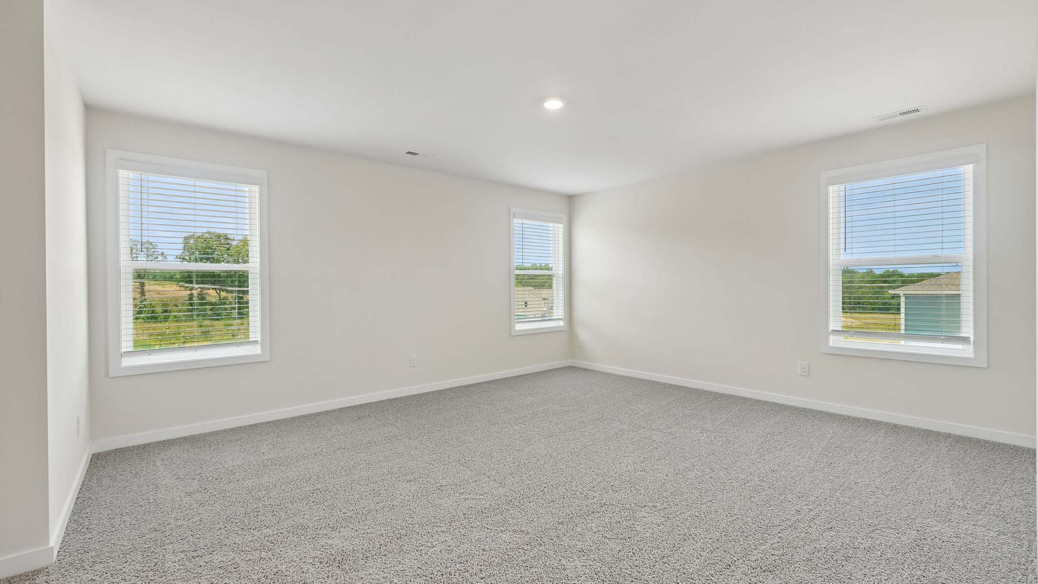 Primary carpeted bedroom with windows