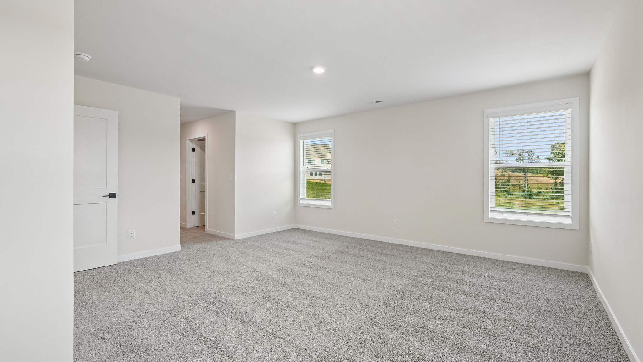 Primary carpeted bedroom with windows