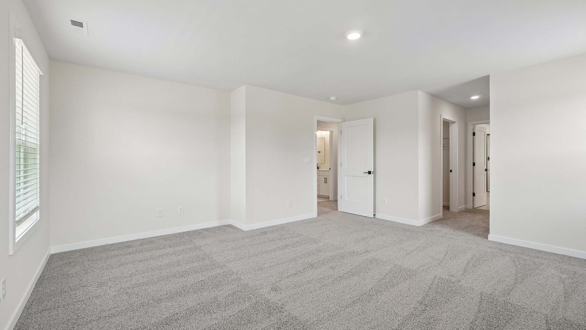 Primary carpeted bedroom with windows