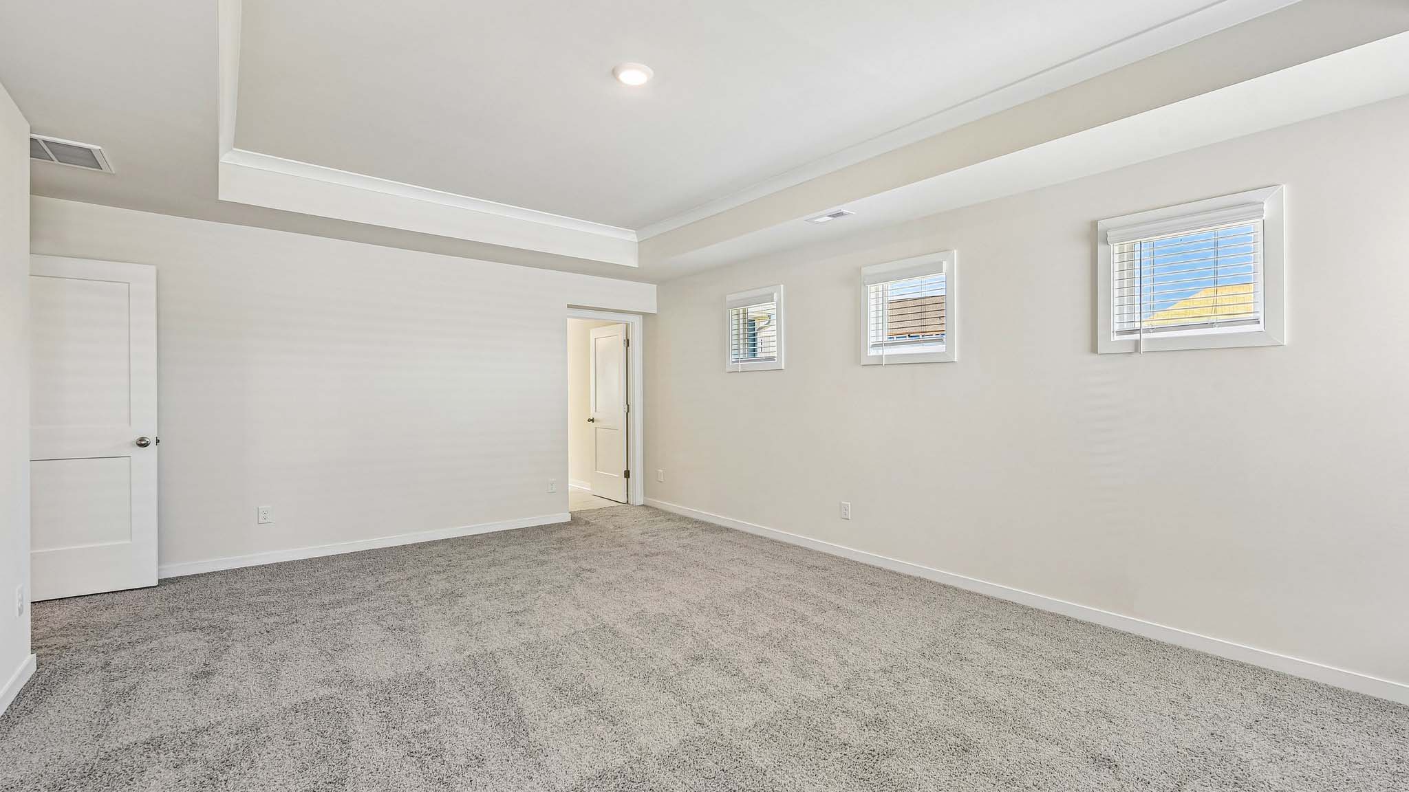Primary carpeted bedroom with windows
