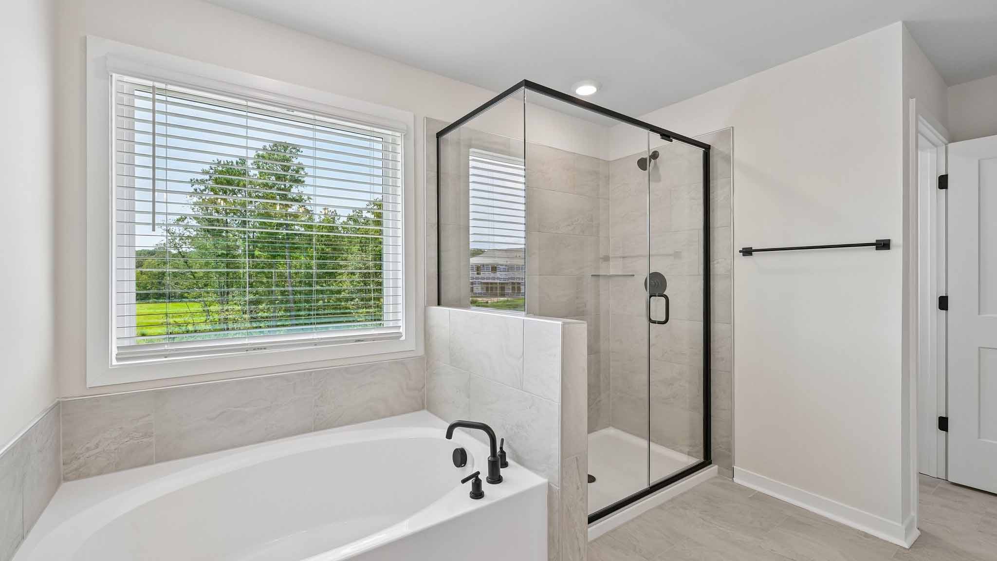Primary bathroom with brown cabinets and standing tub and standing glass shower
