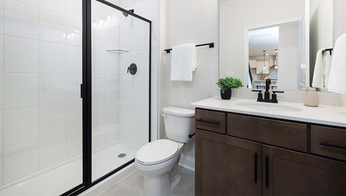 Bathroom with cabinets and white counters, and glass shower