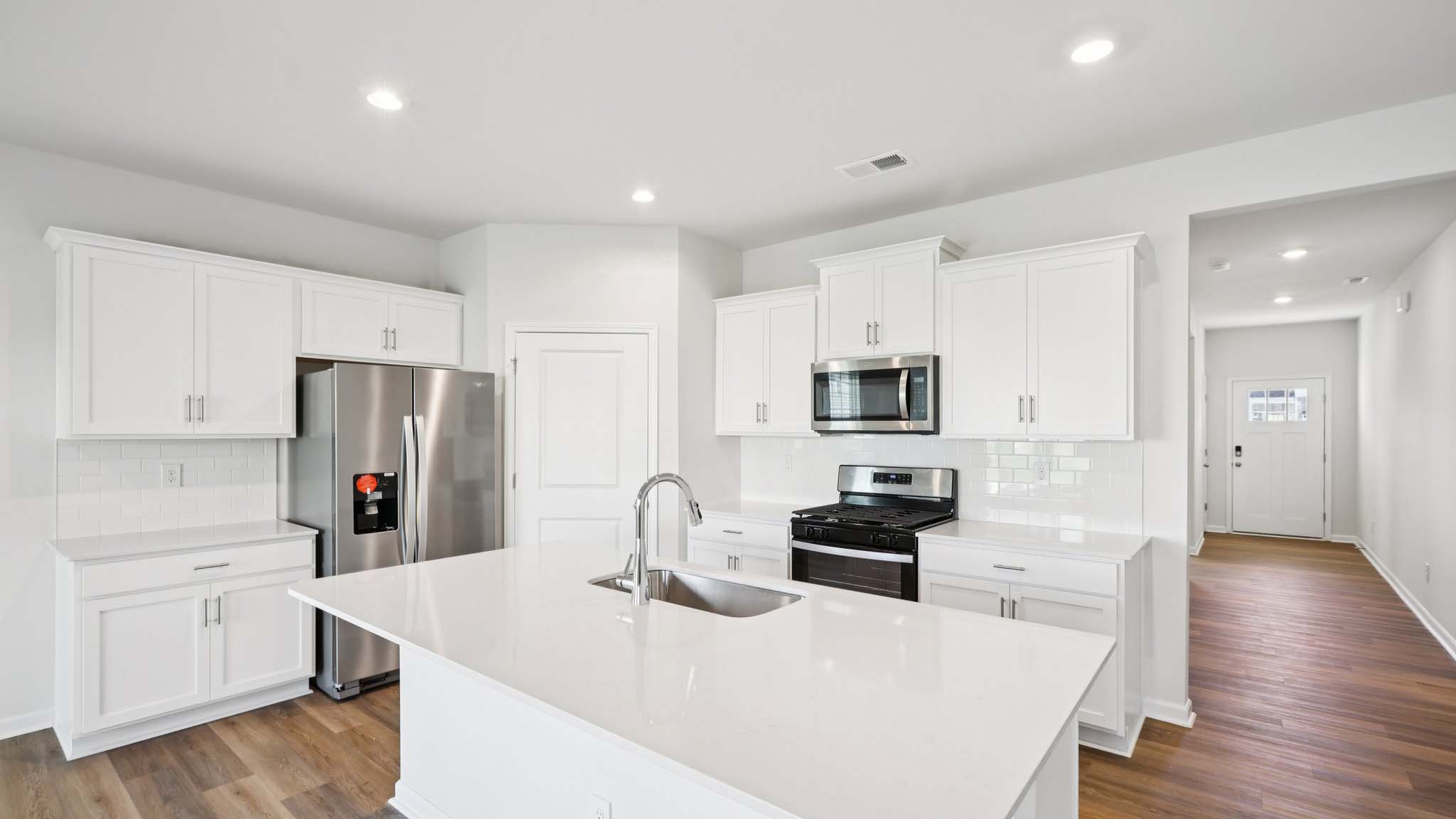 Kitchen and island with white cabinets and subway tiles and stainless steel subway tiles