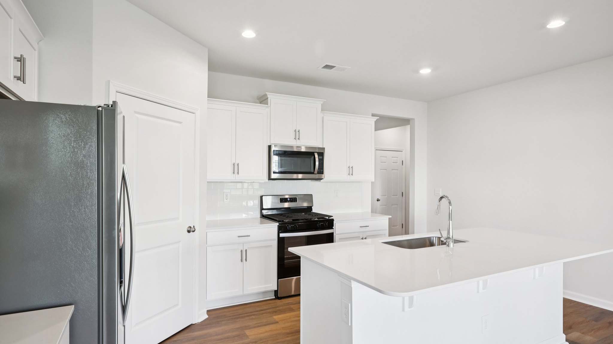 Kitchen and island with white cabinets and subway tiles and stainless steel subway tiles