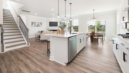 Kitchen and island with white cabinets and counters, wood floors, and stainless steel appliances