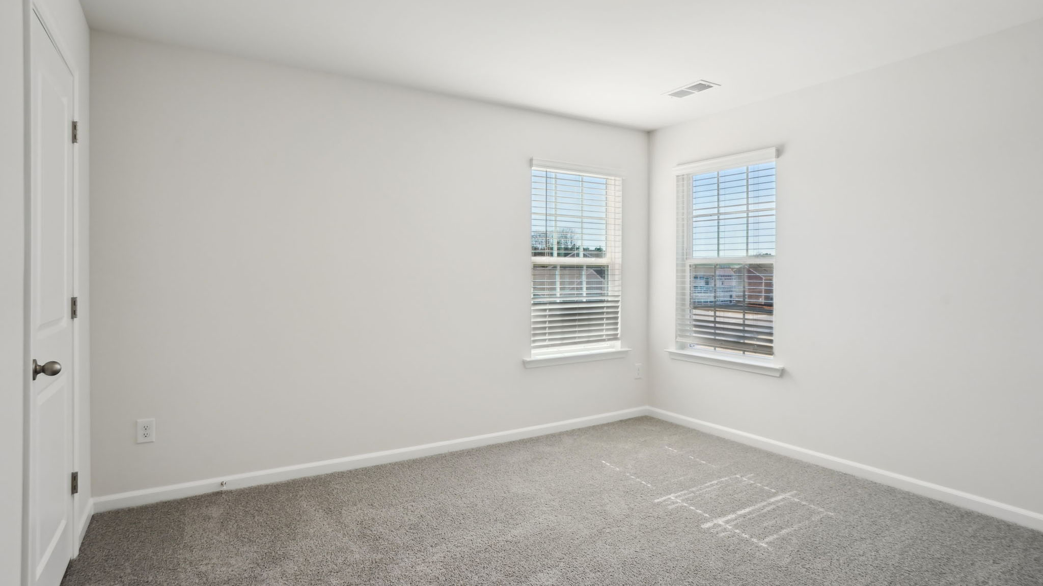 Carpeted bedroom with two large windows