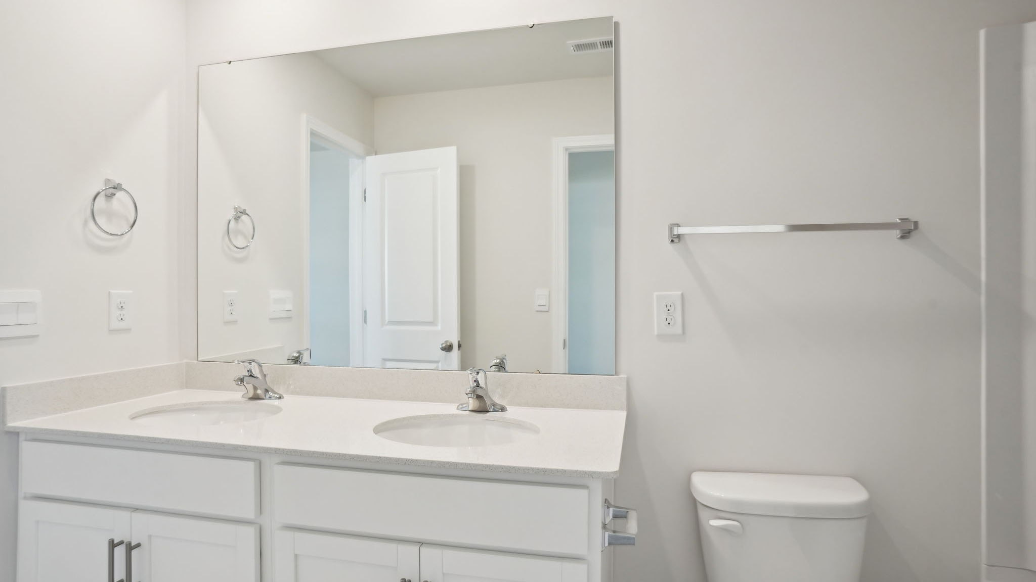Primary bathroom with double sinks, white counters, and cabinets, glass door shower