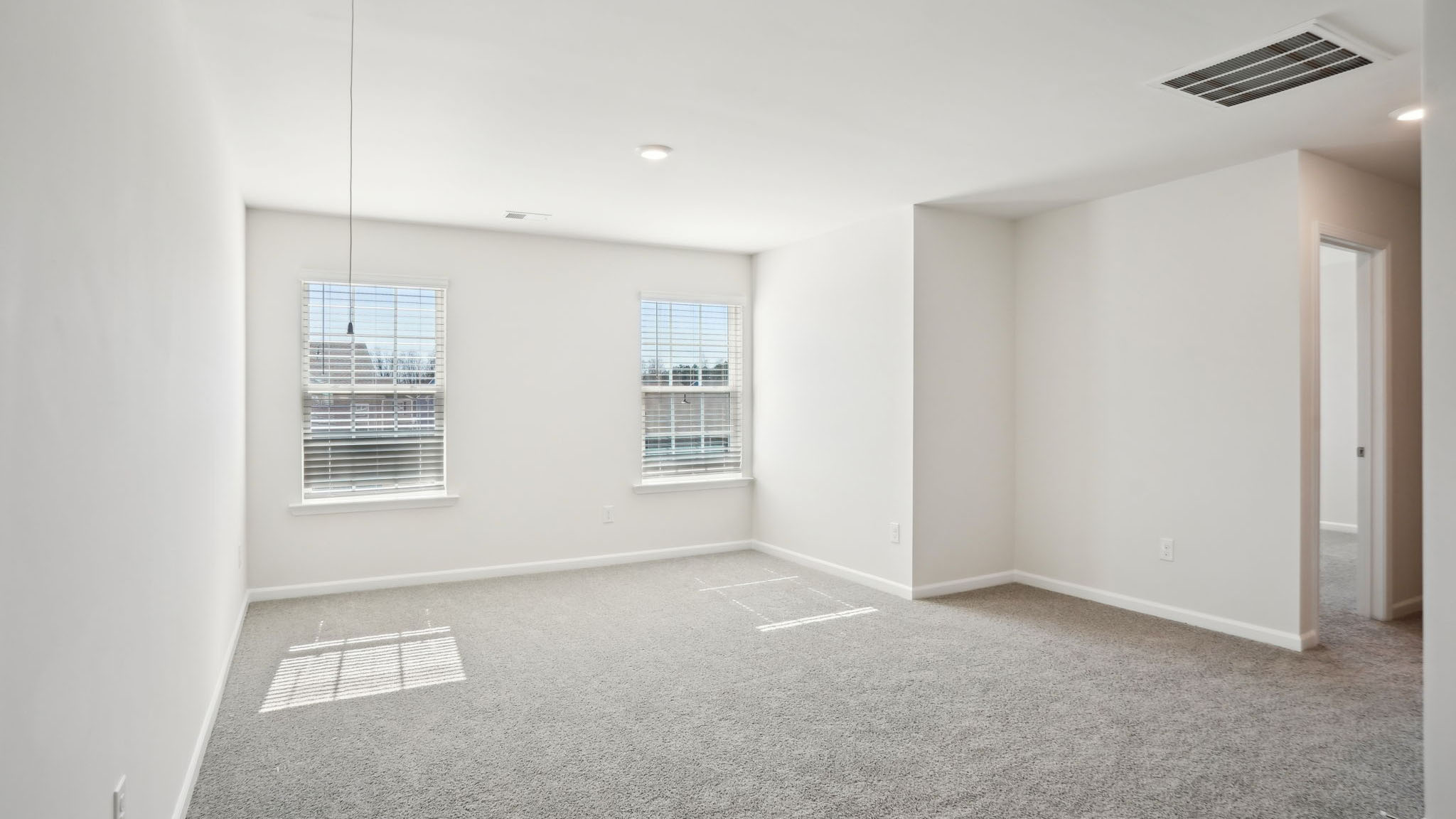 Spacious carpeted upstairs loft space with two large windows