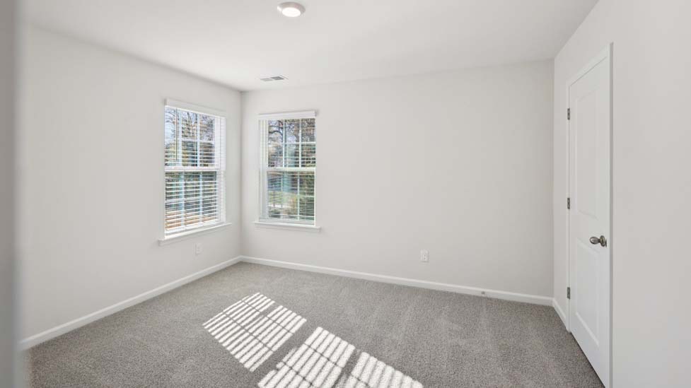 Carpeted bedroom with two large windows