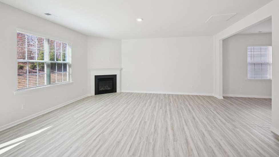 Open family room with fireplace, windows, and view of dining and kitchen