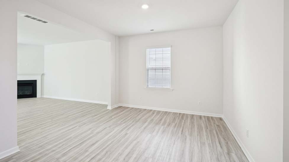 Open family room with fireplace, windows, and view of dining and kitchen