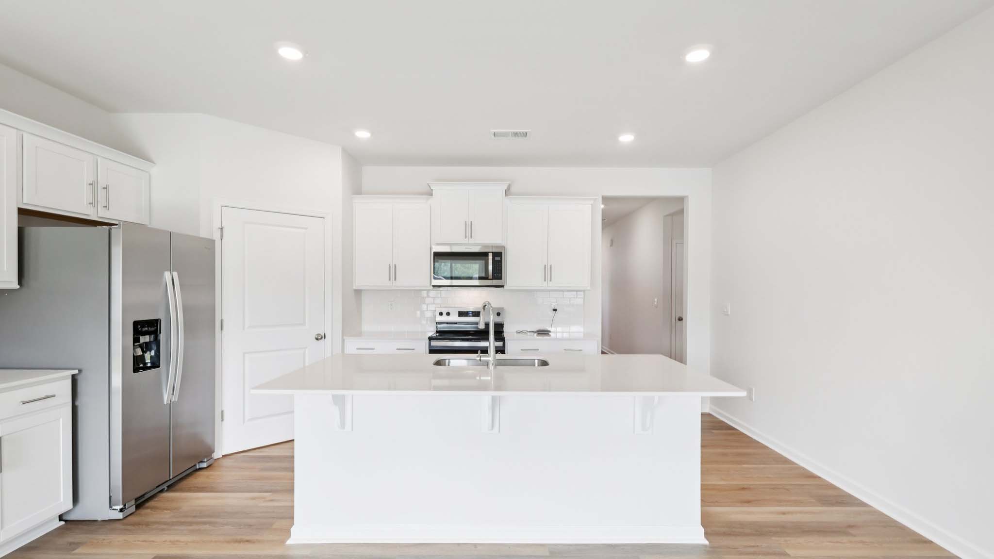 Kitchen and island with white cabinets and subway tiles and stainless steel subway tiles