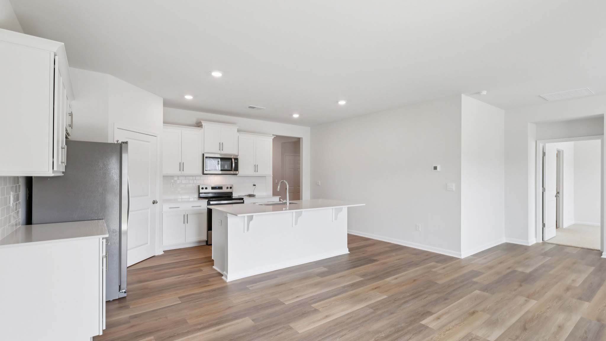 Kitchen and island with white cabinets and subway tiles and stainless steel subway tiles