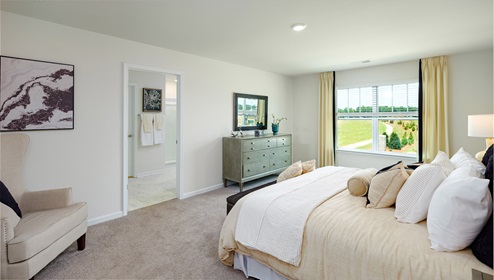 Primary bedroom with large window, carpet and door to bathroom