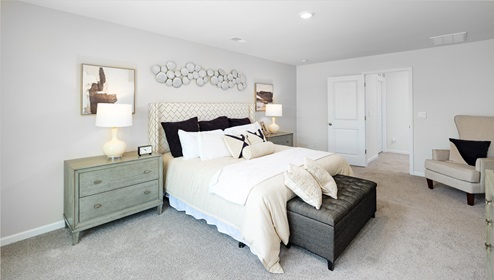 Primary bedroom with large window, carpet and door to bathroom