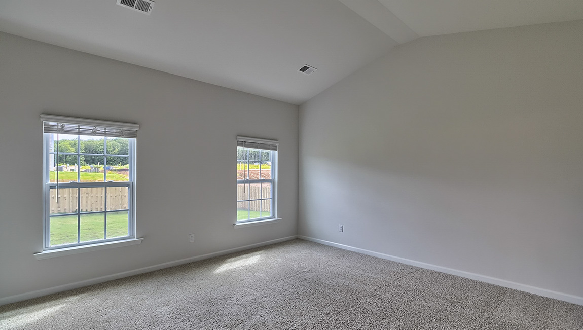 Primary carpeted bedroom with windows