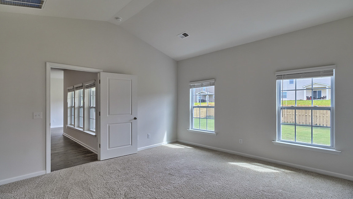 Primary carpeted bedroom with windows