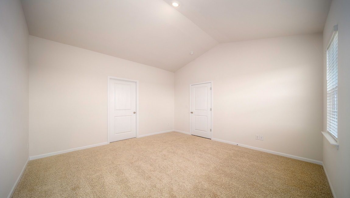 Primary carpeted bedroom with windows