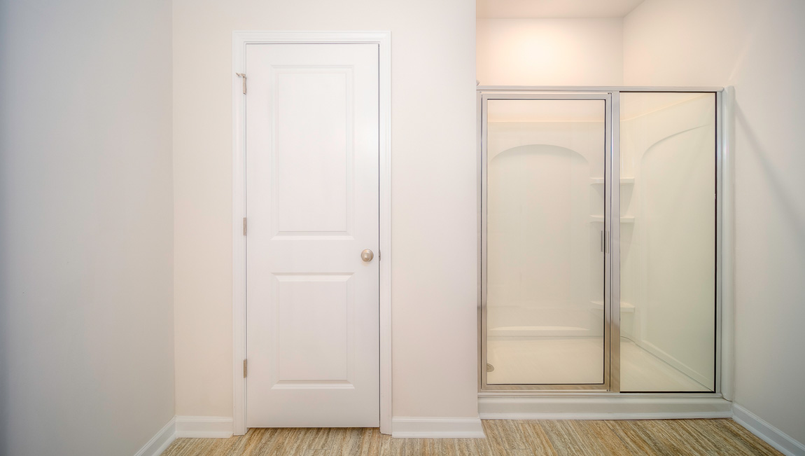 Primary bathroom with double sinks, standing glass shower, and toilet