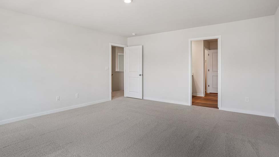 Primary bedroom with wood floors, two large windows