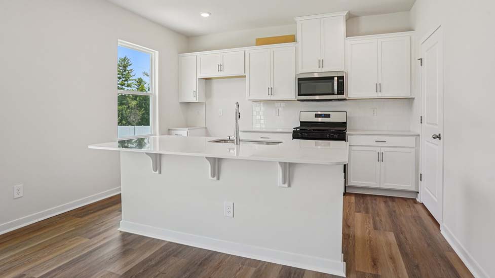 Kitchen with island, white cabinets and wood floors