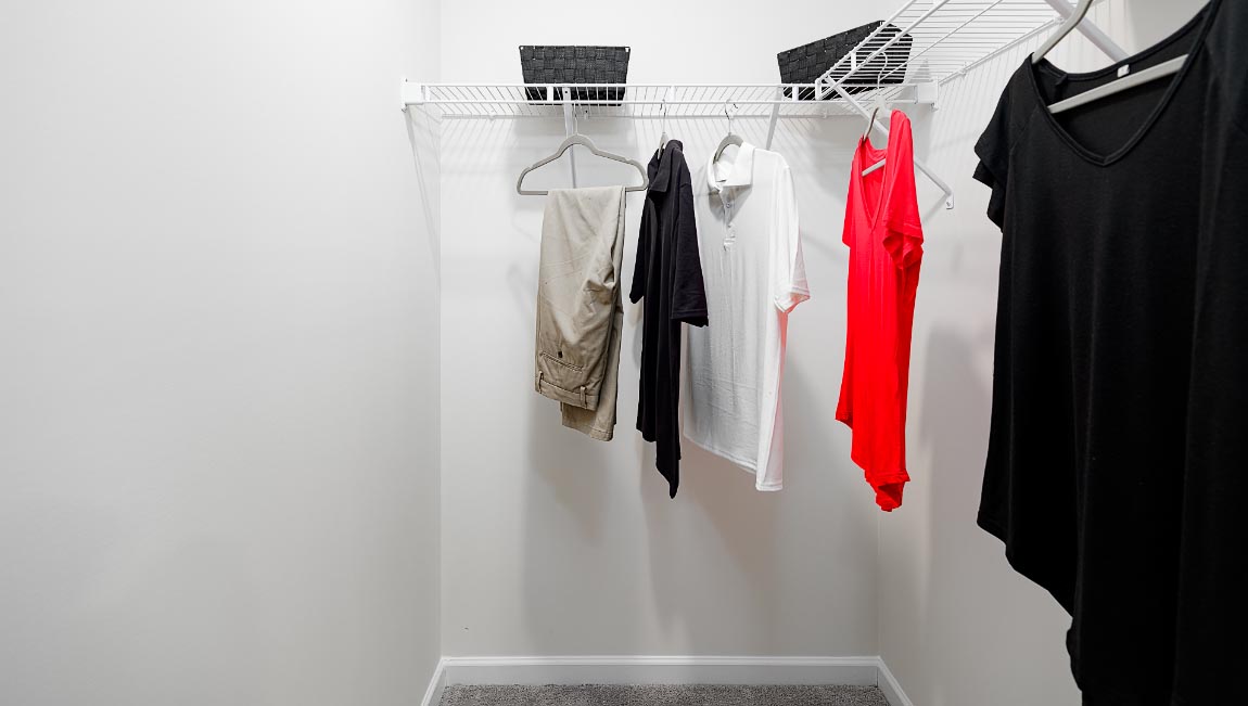 walk in closet, wood floors, and racks