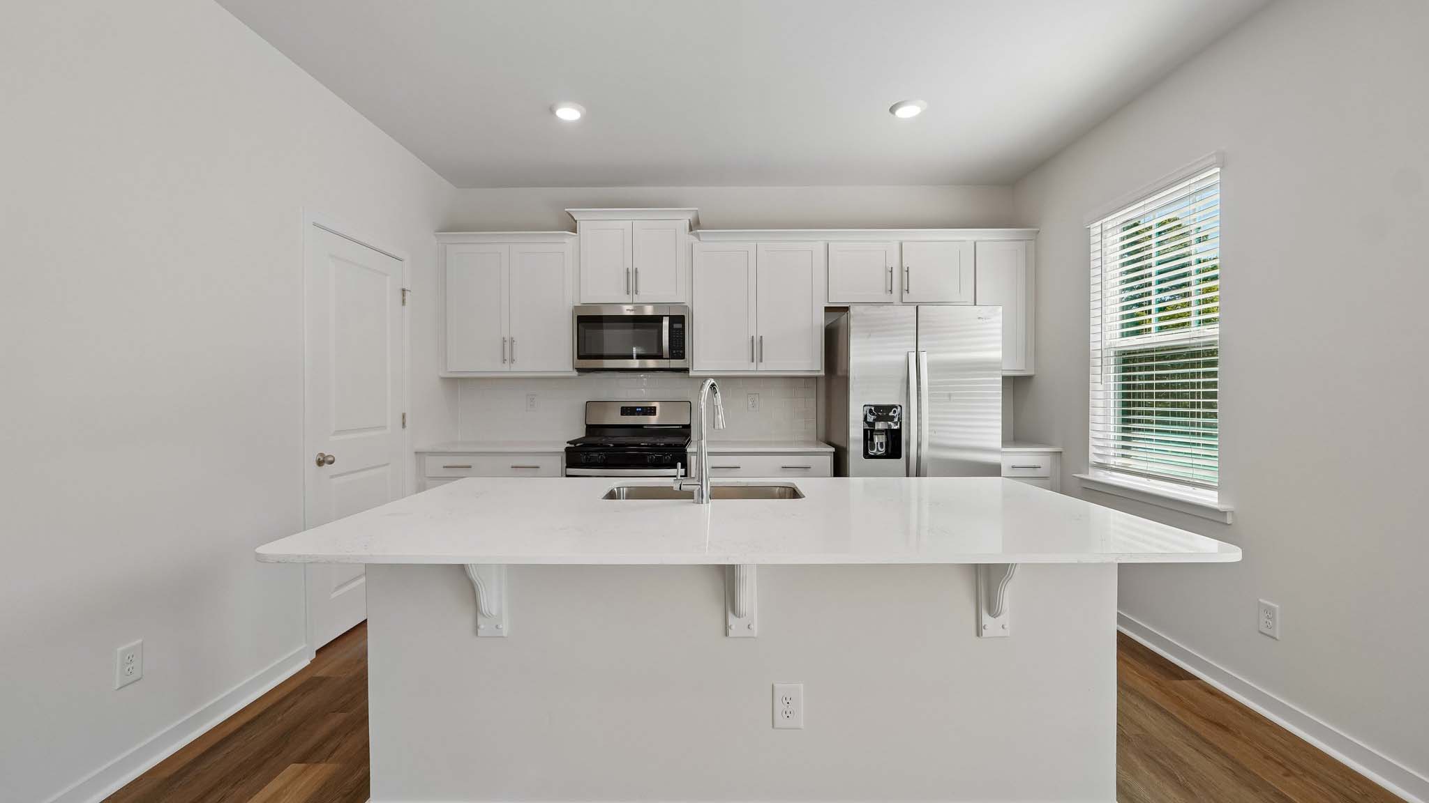 Kitchen with island, white cabinets and wood floors