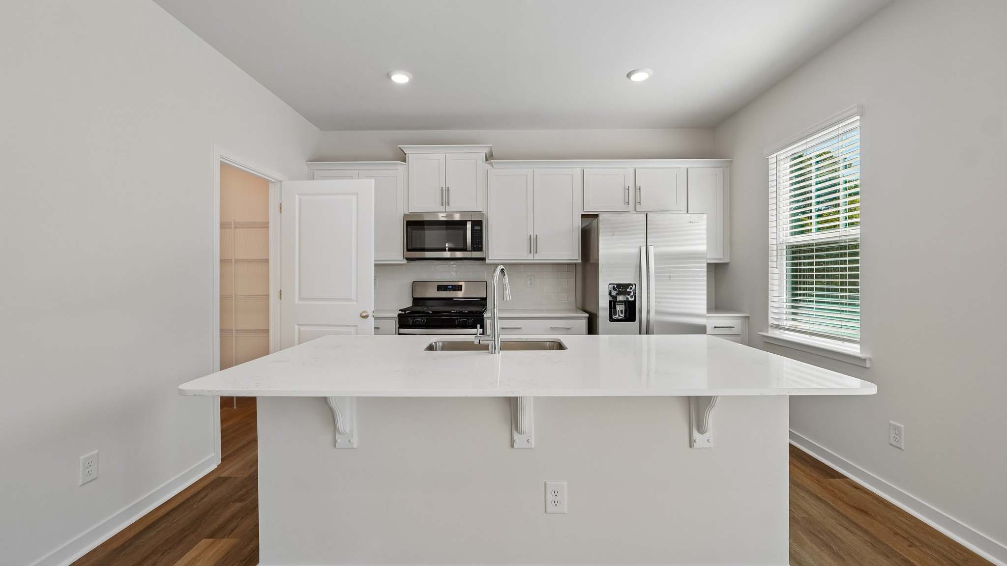 Kitchen with island, white cabinets and wood floors