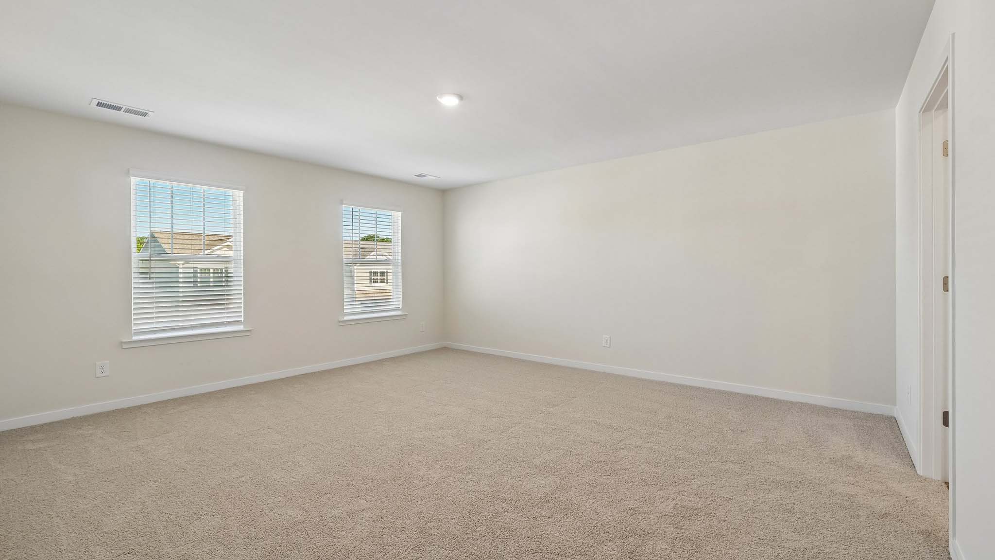 Primary bedroom with wood floors, two large windows