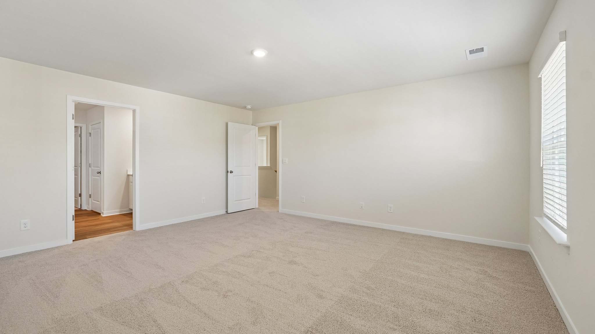 Primary bedroom with wood floors, two large windows